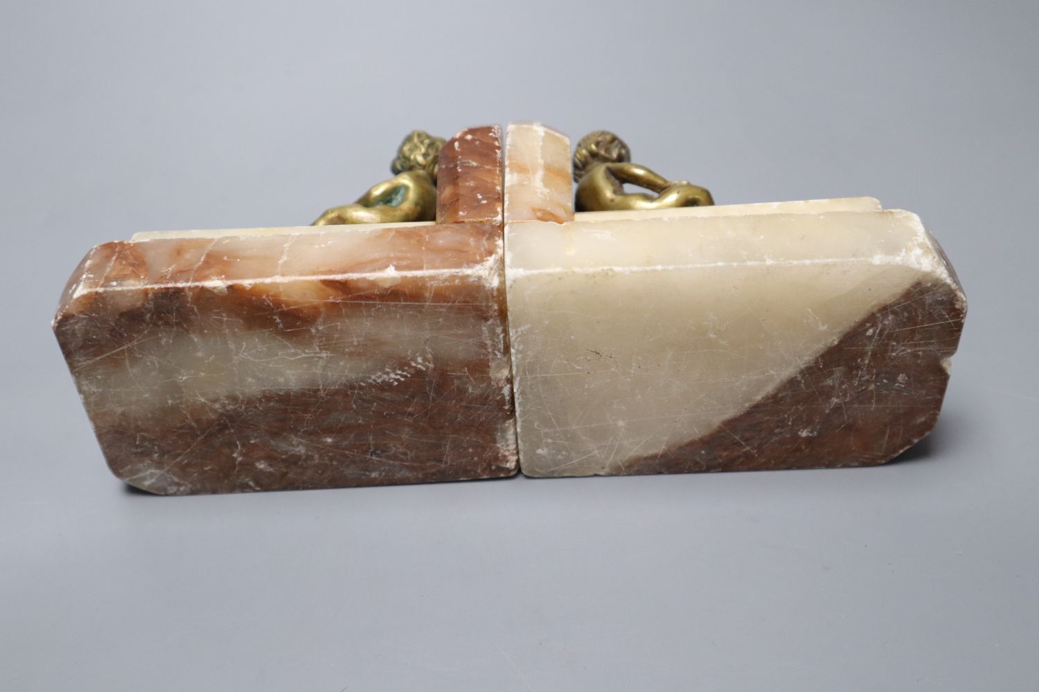 A pair of 1930s stepped marble book-ends, with seated youth surmounts, height 10cm